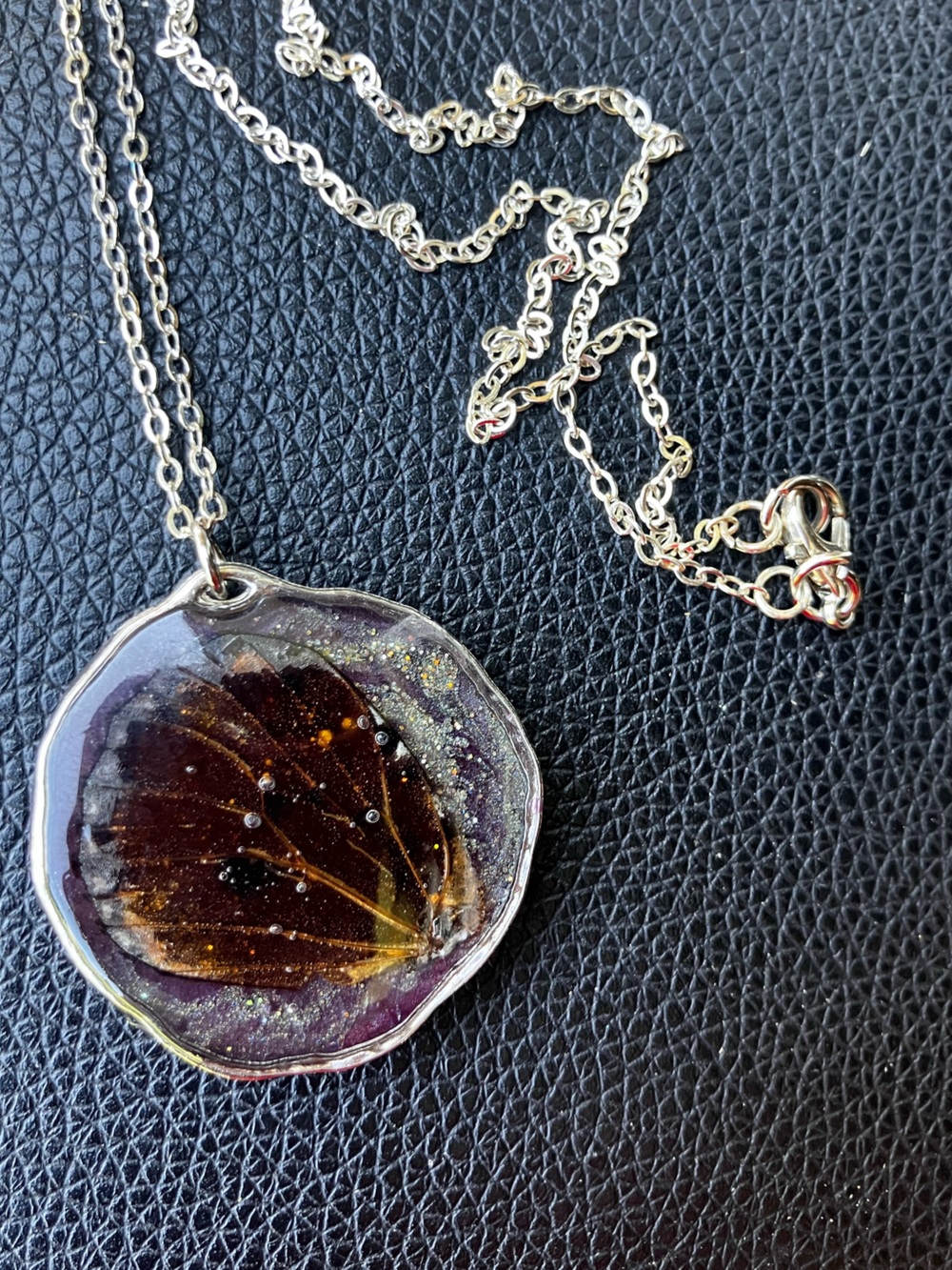 Real butterfly wing necklace with silver hardware and solid background